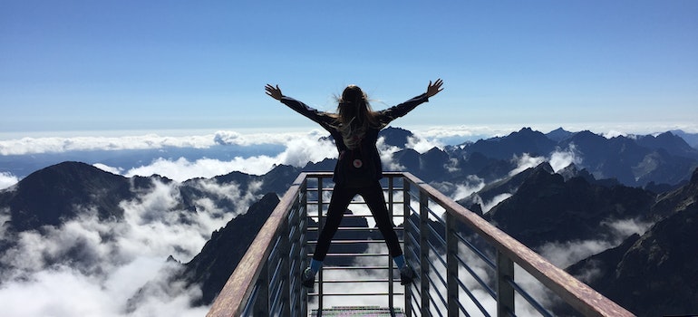 A woman spreading her arms toward the wild while standing on a high observation deck
