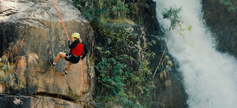 A man rock climbing near a waterfall as adventure therapy for addiction recovery in West Virginia