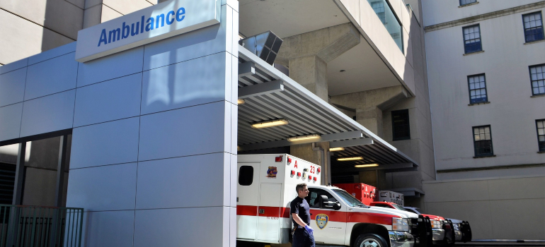 A hospital building, with ambulances and a paramedic, helping with opioid overdose treatment.