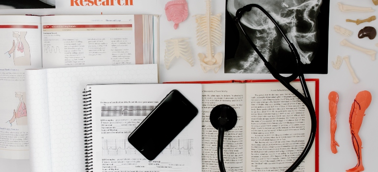 A phone and a CT scan on the table next to many books. 