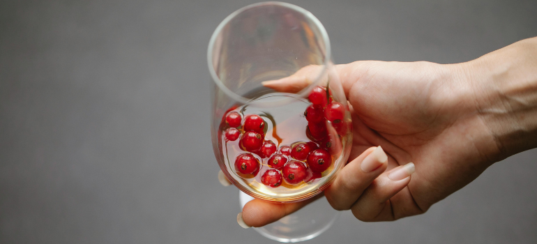 A person holding an alcoholic drink with red berries inside