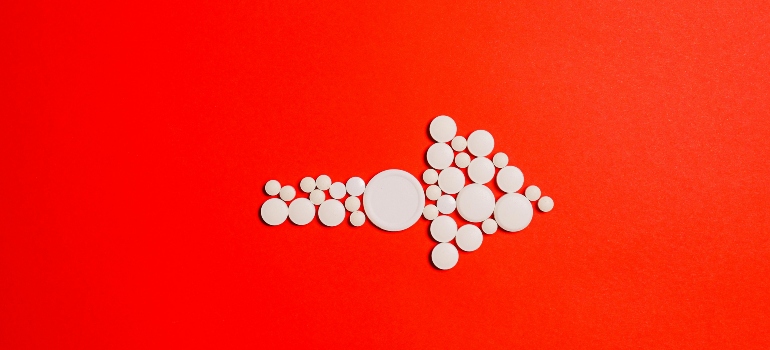 White pills in the shape of an arrow on a red background