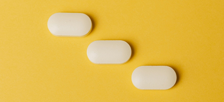 Three white pills on a yellow background
