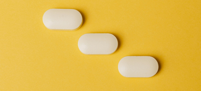Three white pills on a yellow background