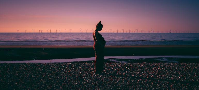 Pregnant woman standing on the beach.