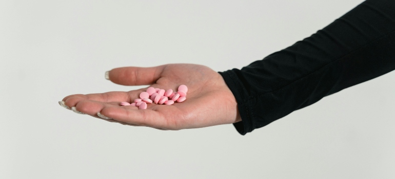 A person holding pink pills that are drugs associated with violent acts