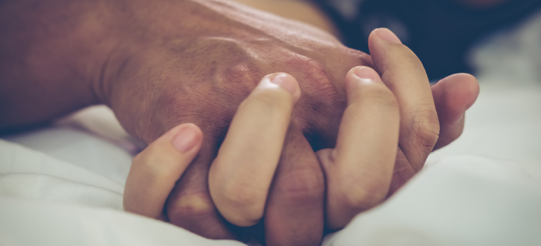 Two people holding hands in bed