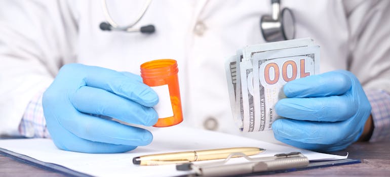 Doctor holding medication in one hand and money in the other hand.