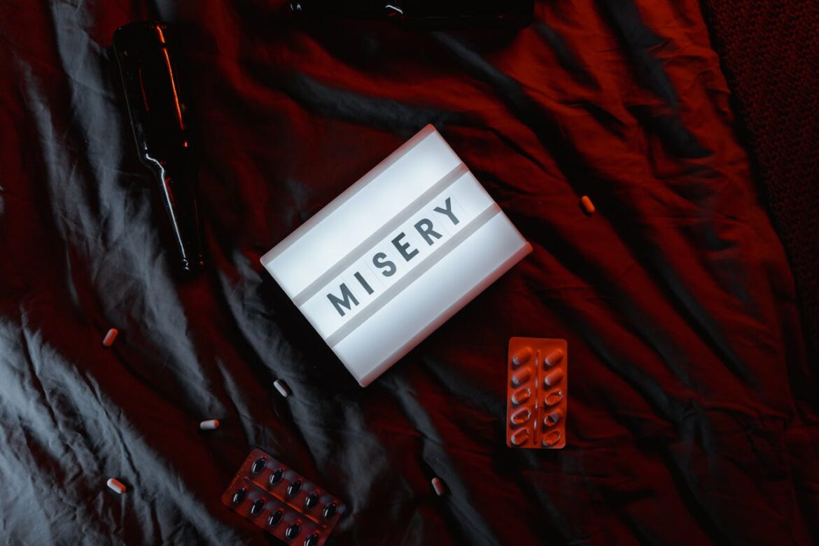 Beer bottle and pills on a bed sheet.