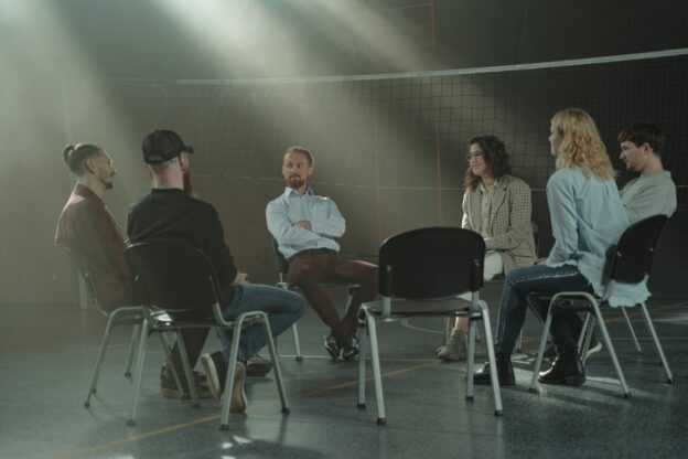 People sitting in a circle and talking about who started AA and how it helped them.