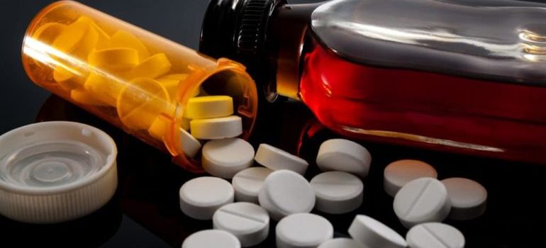 Bottle of pills next to a bottle of alcohol.