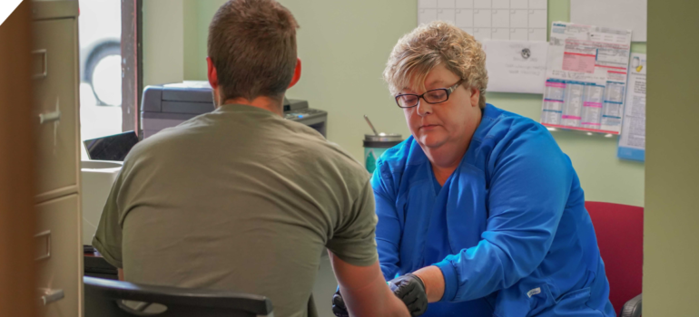 A medical professional drawing blood from a patient at a rehab center