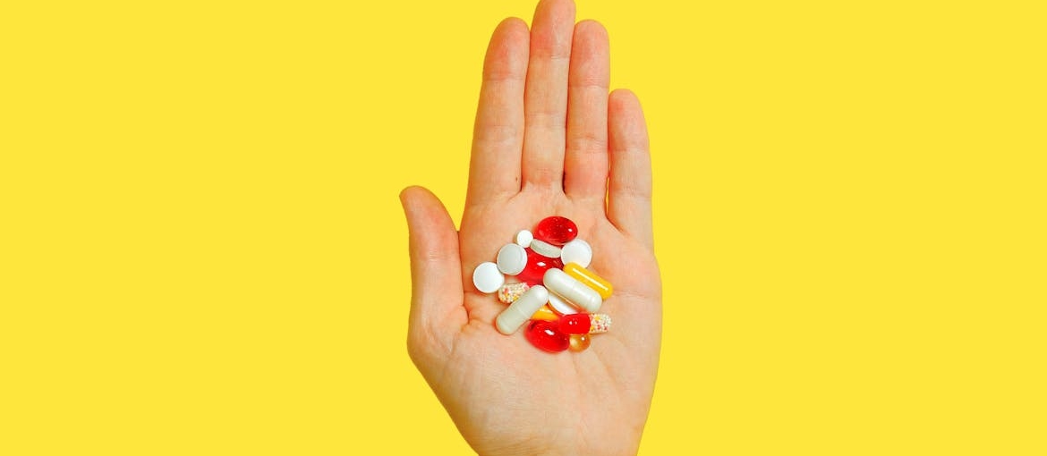 Person holding different types of vitamins.