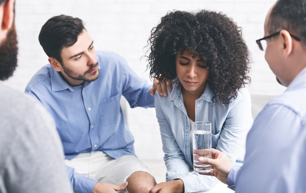 Rehab Community Members Supporting Upset Afro Woman At Therapy Session