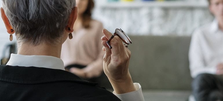 A therapist holding her glasses as she listens to her clients.