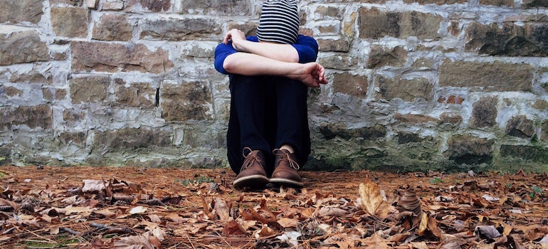 Person hugging their knees on the ground.