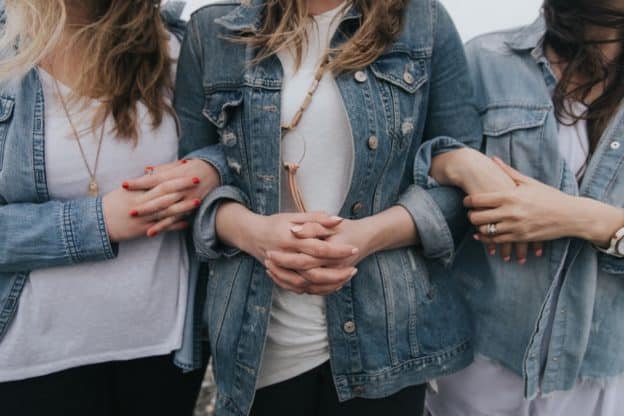 Three women with their arms linked.