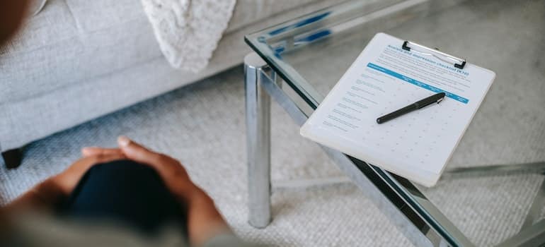 A close-up of a therapist’s clipboard on a glass table.