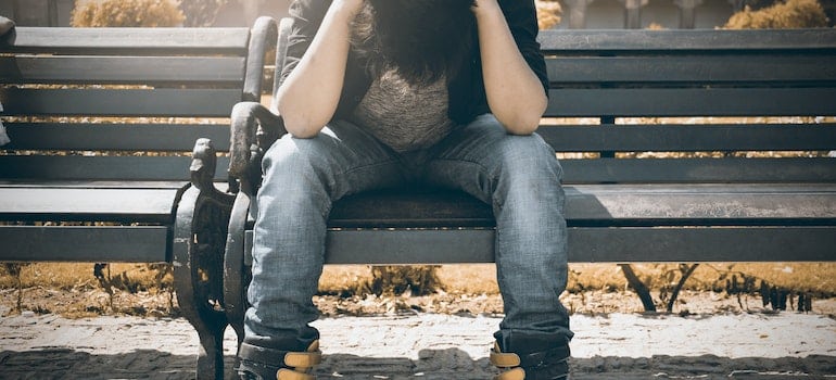 Man sitting on a bench with his head in his hands.