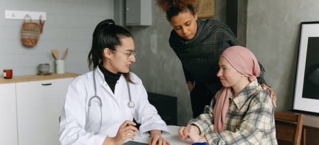 Two women having a conversation with a doctor indoors.