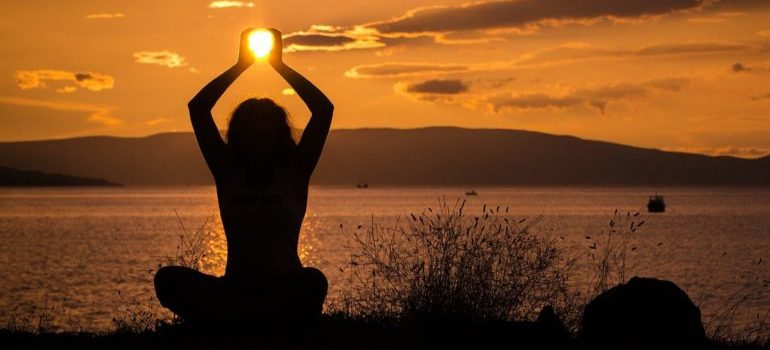 A silhouette of a woman at the beach holding the sun.