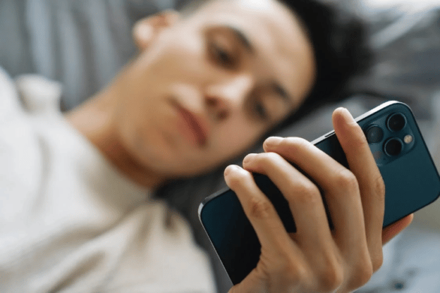 A young person in bed using a mobile phone.