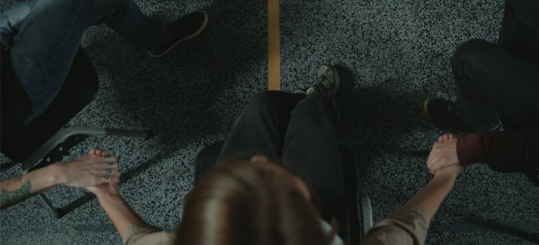 A close-up of people holding hands during a group therapy session.