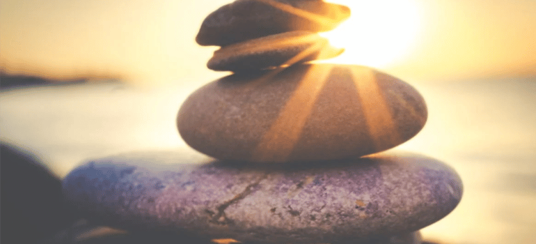 Small rocks balanced on each other under the sunset.