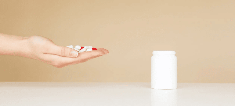 A close-up of a person holding white pills in their hand.