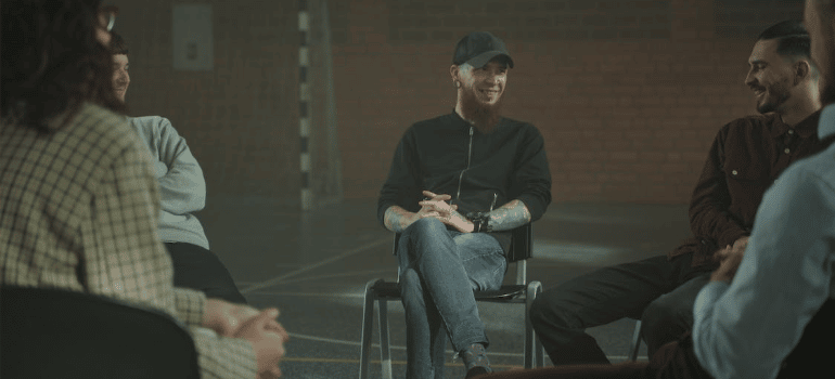 A group of people discussing during a group therapy session indoors.