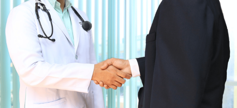 A close-up of a doctor and a patient shaking hands.