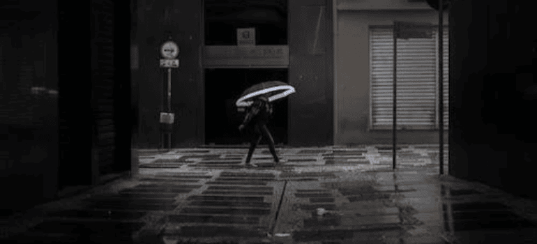 A person with an umbrella walking in an alley.