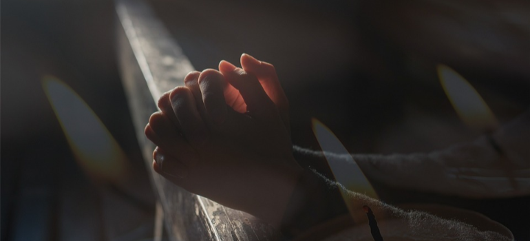 A close-up of a person’s hands held together in prayer.