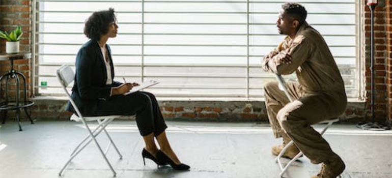 A therapist and her patient during a therapy session by a window.