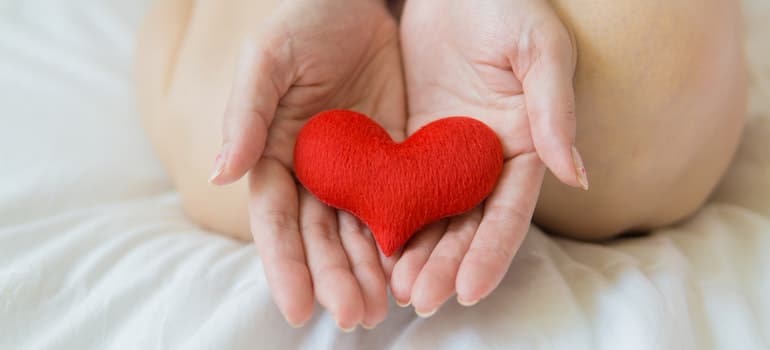 Person holding a red felt heart in their hands.