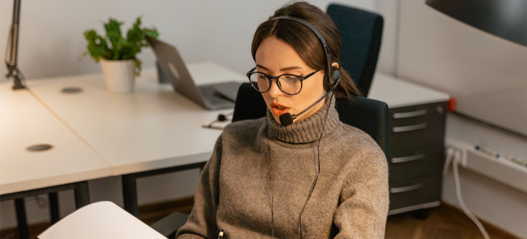 A female support agent in a brown shirt working in an office as she reads a paper.