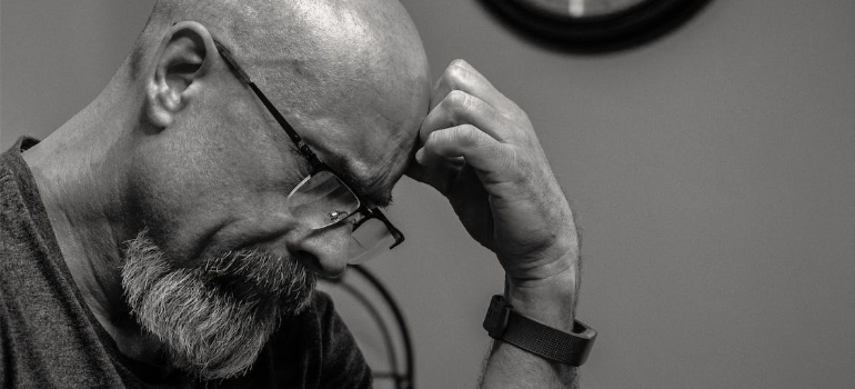A stressed man holding his head in thought.