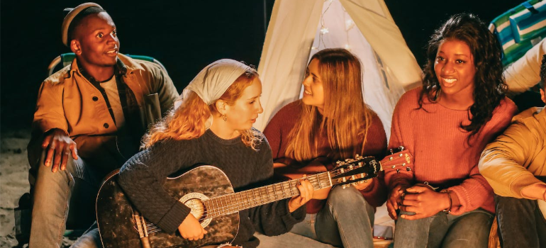 A group of people hanging out and singing at the beach.