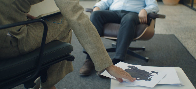 A psychotherapist reaching for Rorschach tests during a therapy session.