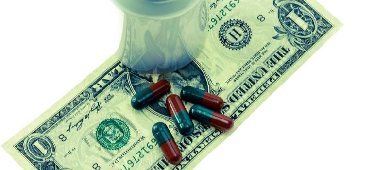 Medicine pills and a bottle on a dollar bill.
