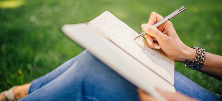 A close-up of a woman keeping a journal outdoors.