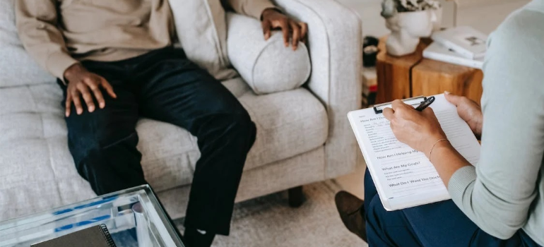 A crop of a man sitting on a couch during a psychotherapy session.
