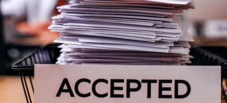A close-up of a pile of papers, labeled “accepted”.