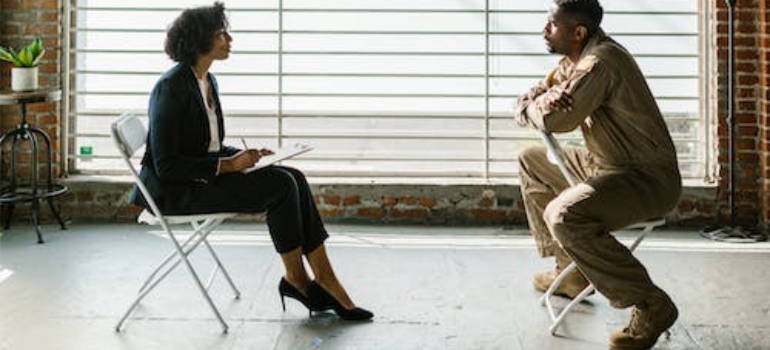 A female psychotherapist and a male patient in an army uniform during a psychotherapy session.