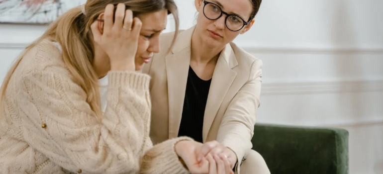 A female psychotherapist counseling a sad female patient on a couch.