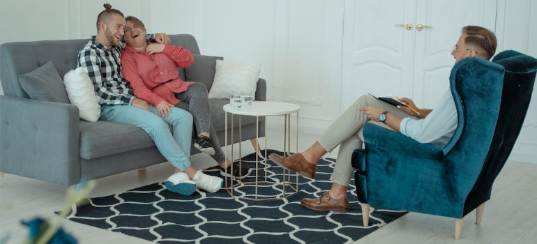 A psychotherapist and a happy couple on the couch during a therapy session.