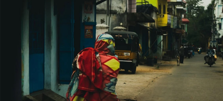 A person walking by weathered houses at night.