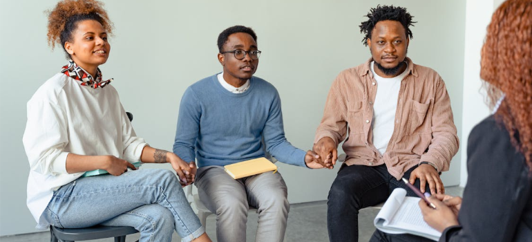 A group of friends holding hands during a group therapy session.