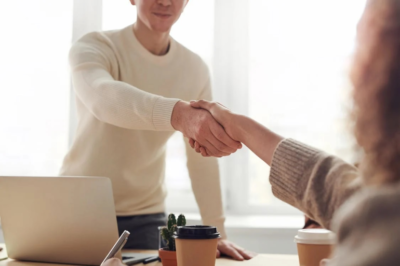 A man and a woman shaking hands over a table.