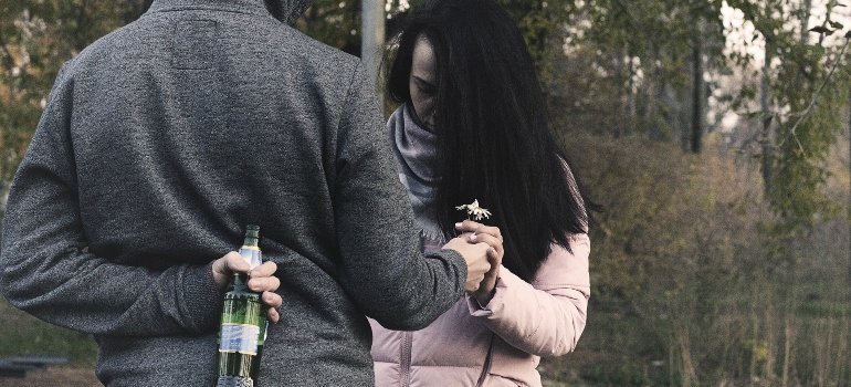 person holding a beer bottle behind their back